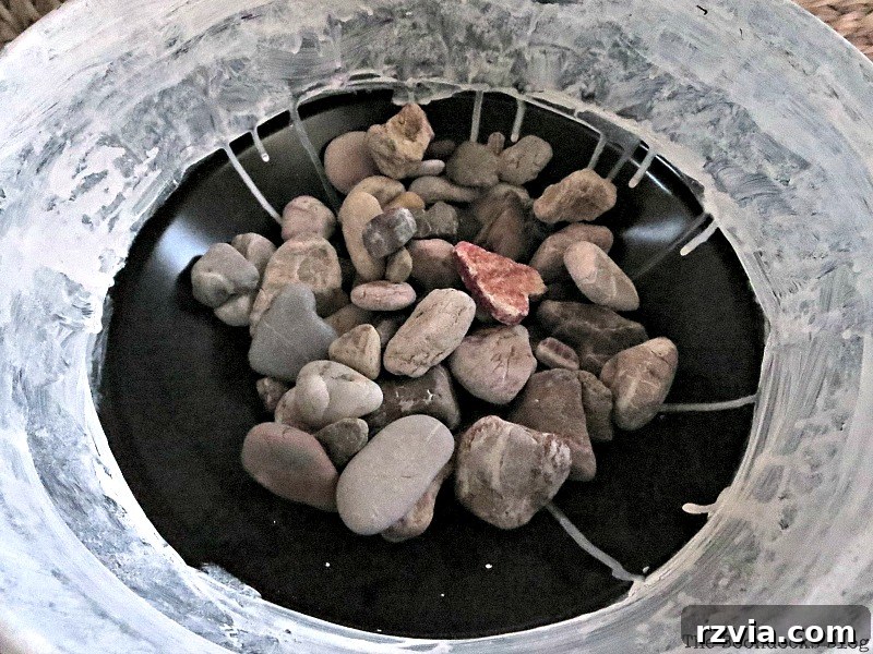 Adding rocks for essential drainage inside the repurposed grill planter, preparing it for plants