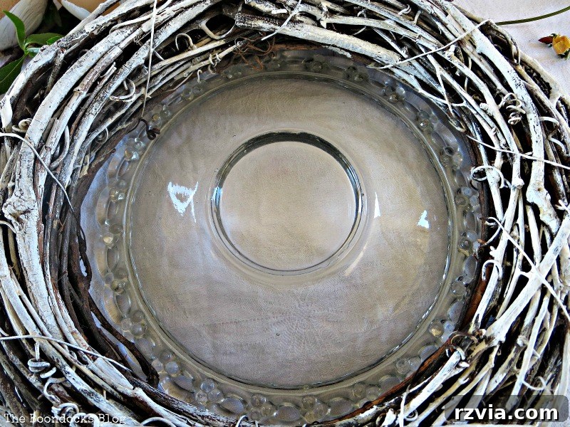 White-painted wreath being placed on top of the glass plate to form the nest's foundation