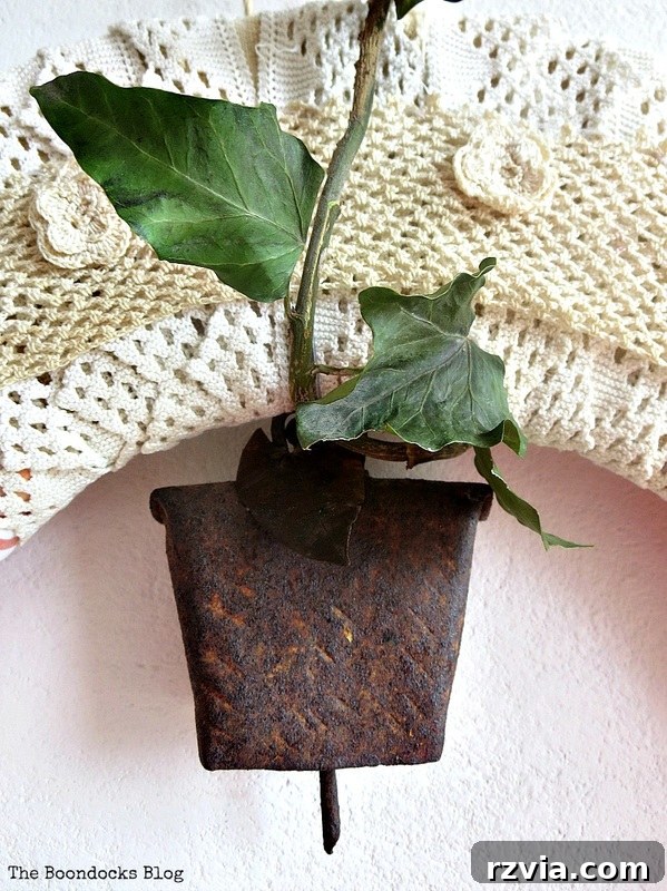 Close-up of an old, patinated bell and fresh greenery intertwined, adding a rustic charm to a DIY almond blossom wreath.