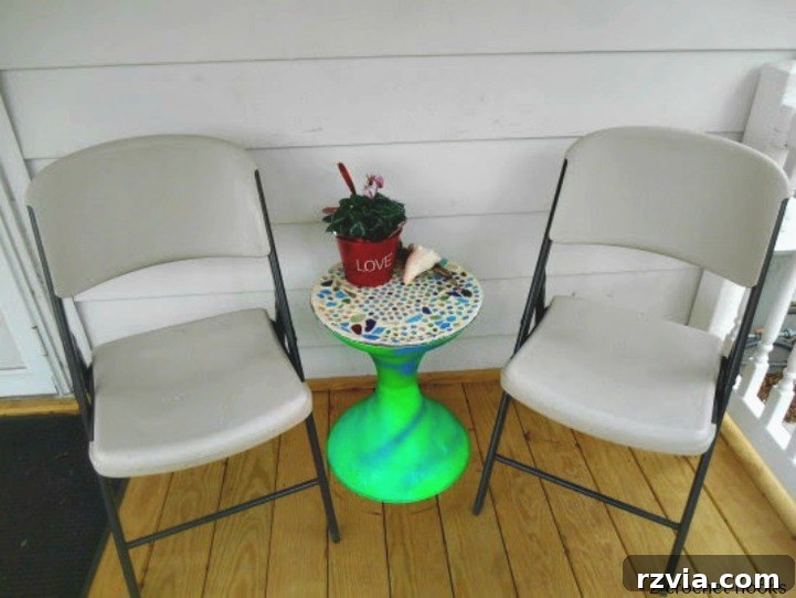Craft Your Own Sea Glass Mosaic Table 11 The vibrant, completed sea glass mosaic table top resting beside two simple folding chairs, awaiting its permanent matching Adirondack chairs.