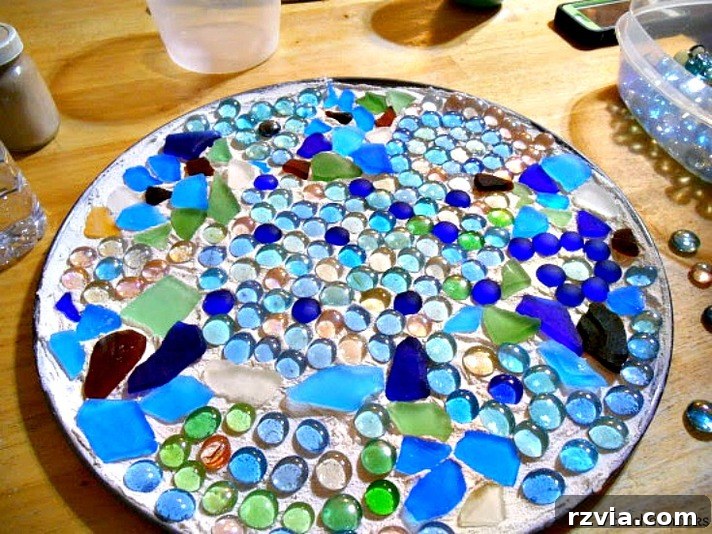 Craft Your Own Sea Glass Mosaic Table 7 A close-up view of the pizza pan, now beautifully covered with an intricate mosaic of sea glass and marbles, showcasing the diverse textures and colors.