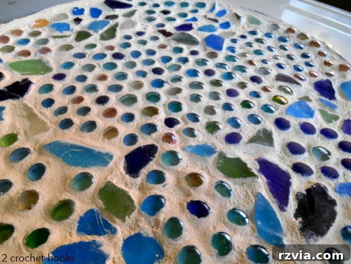 Craft Your Own Sea Glass Mosaic Table 9 A detailed close-up shot of the sea glass and marble tabletop after grouting and initial cleaning, revealing the sparkling beauty of the mosaic elements.