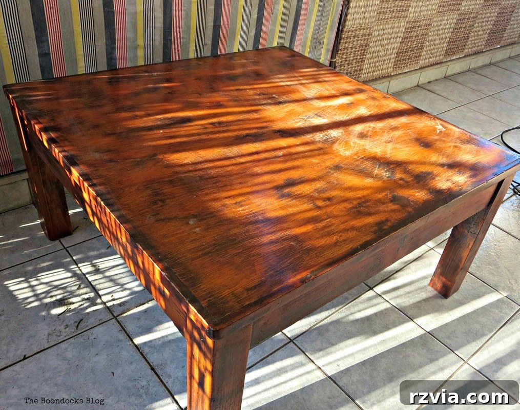 Vibrant Tri-Tone Reclaimed Coffee Table 3 An old, orange-toned wooden coffee table showing signs of wear and tear before refurbishment