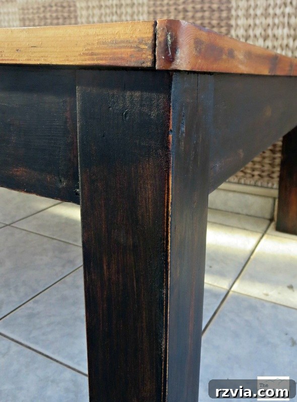 Vibrant Tri-Tone Reclaimed Coffee Table 9 Close-up of the coffee table legs painted with black chalky paint and lightly distressed, showing the wood peeking through.