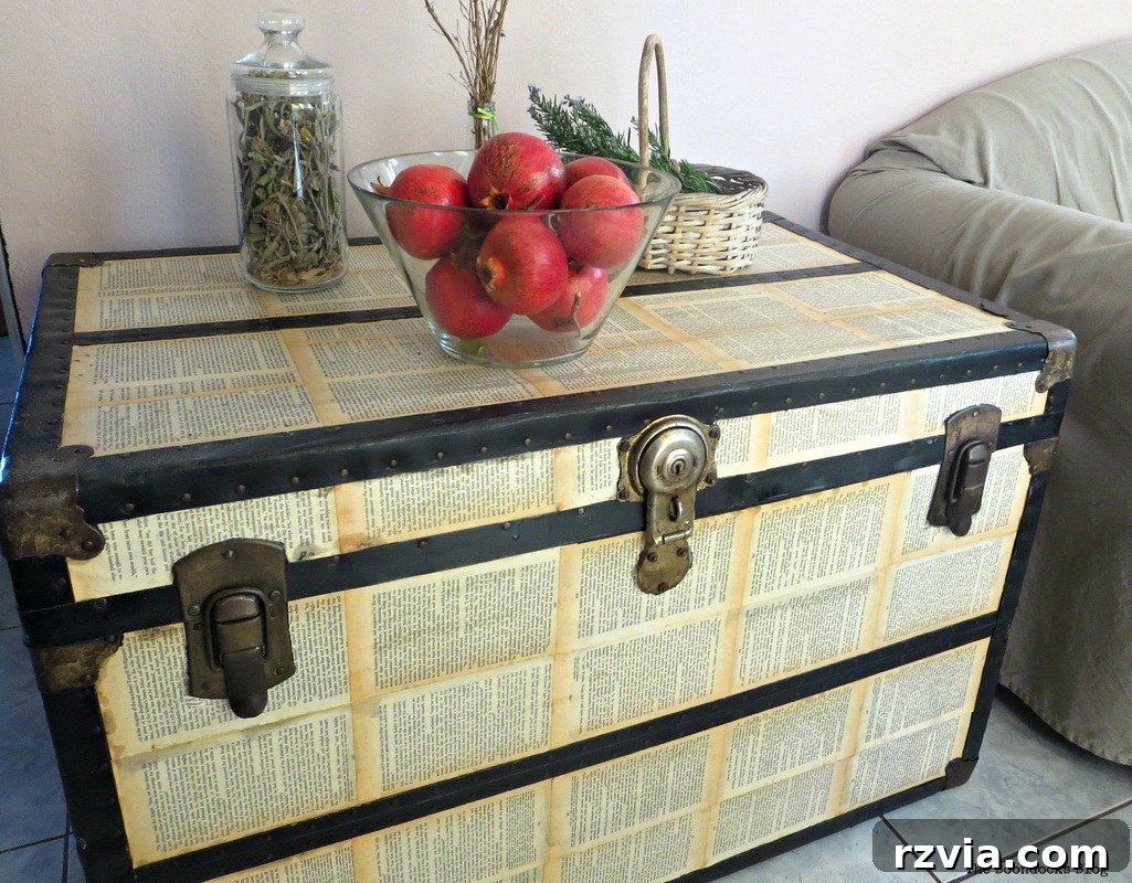 The finished decoupaged metal trunk serving as a stylish side table in a living room setting