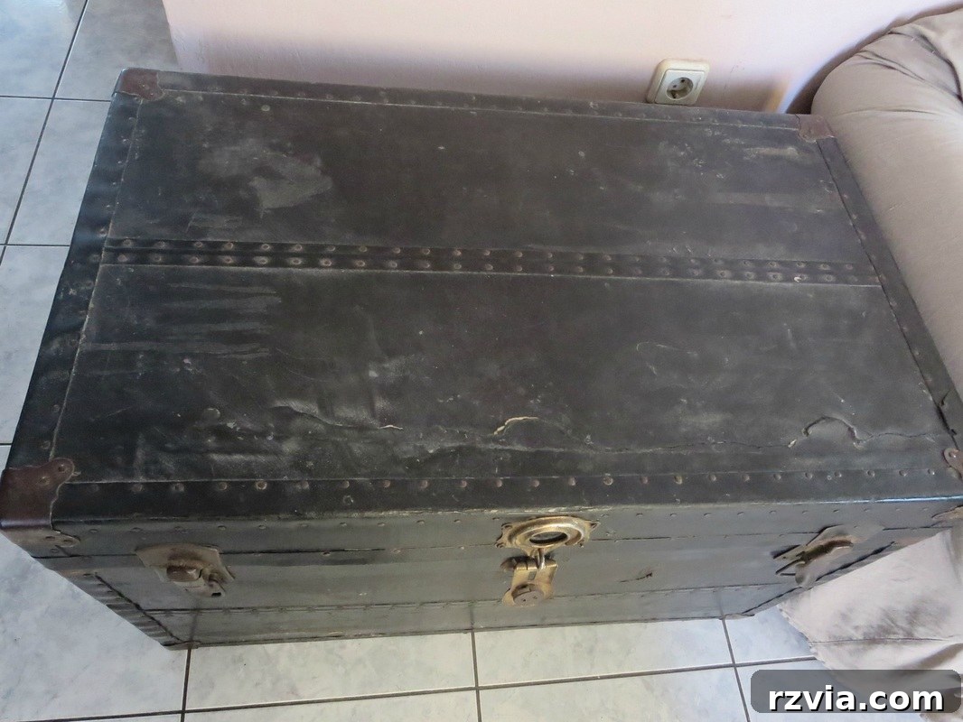 Close-up of the antique metal trunk showing wear and tear before restoration