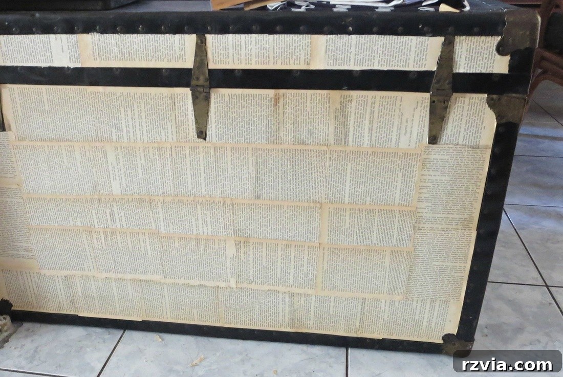 Vintage trunk partially covered with pages from an old book, showcasing the decoupage process