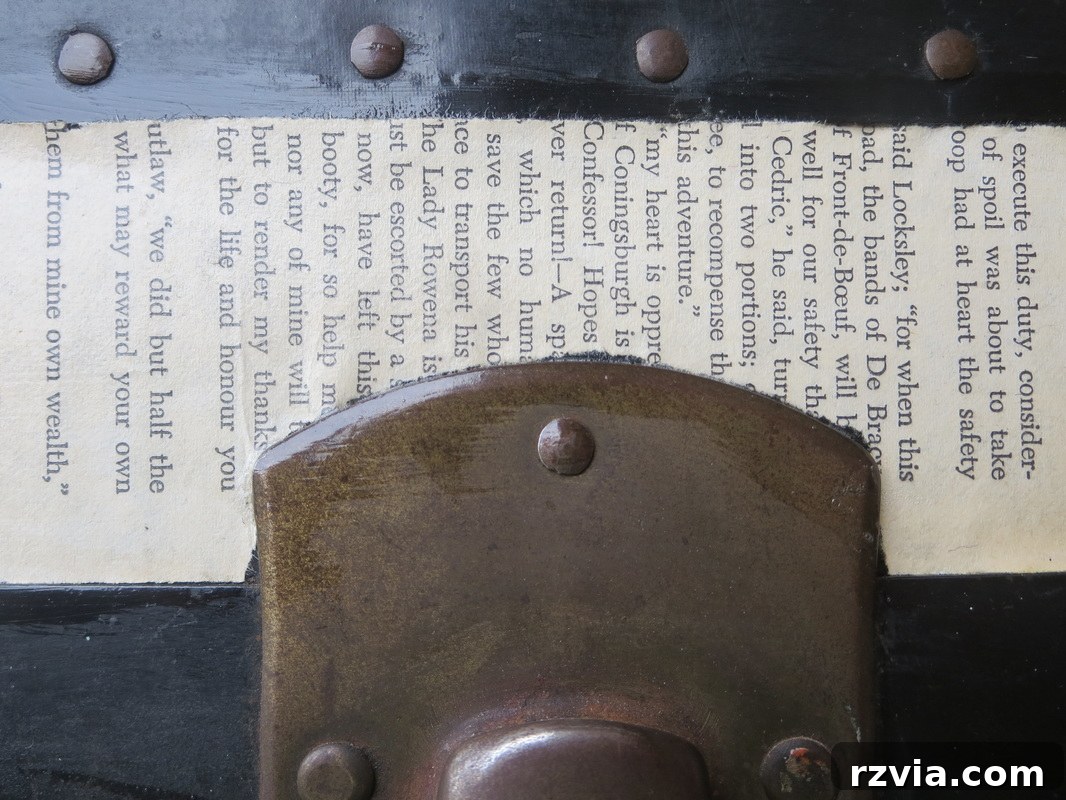 Close-up detail of the vintage trunk showing book pages meticulously decoupaged around metal accents